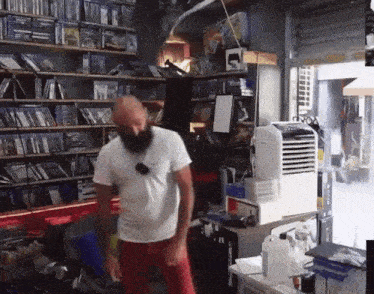 a man with a beard is dancing in a store with shelves full of video games