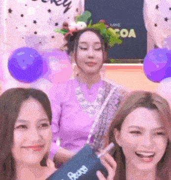 three women are posing for a picture in front of balloons and a sign that says " coa "