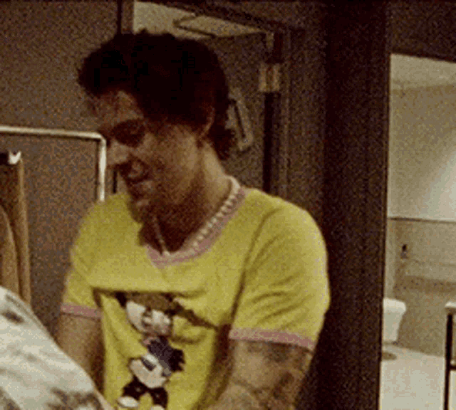 a man is wearing a yellow shirt with a mickey mouse on it