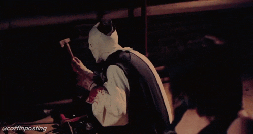 a man in a clown costume is holding a hammer next to a woman
