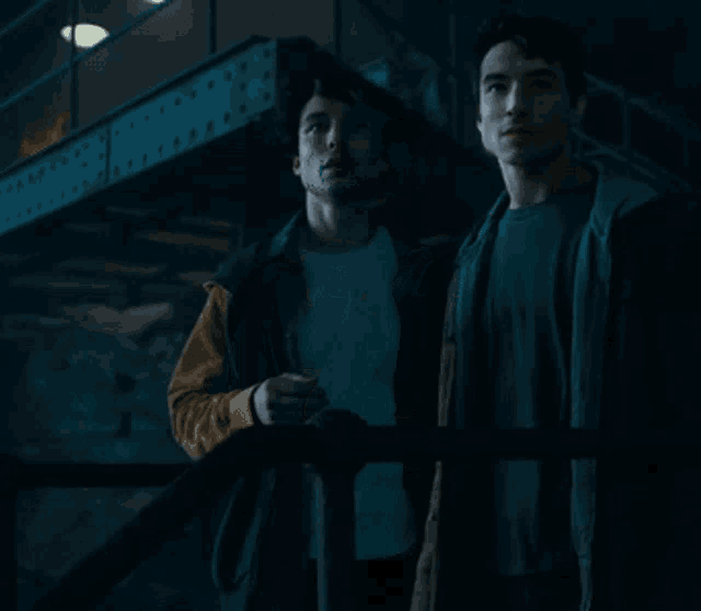 a couple of men standing next to each other in a dark room