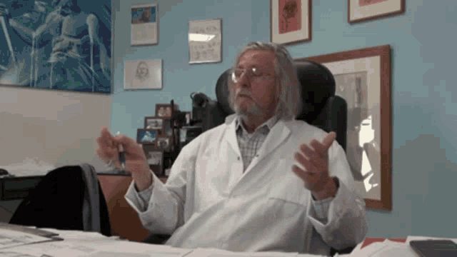 a man in a white lab coat sits at a desk