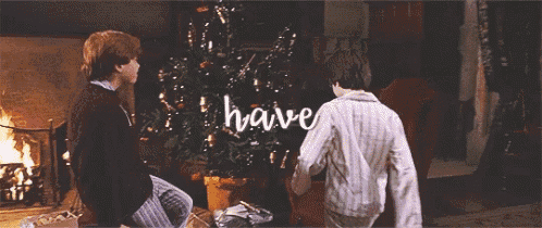 two men are sitting in front of a fireplace and a christmas tree with the words have written on it