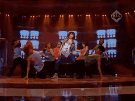 a group of dancers are performing on a stage with a trans logo in the background