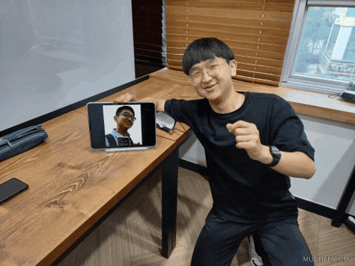 a man sitting in front of a tablet with a picture of him on the screen