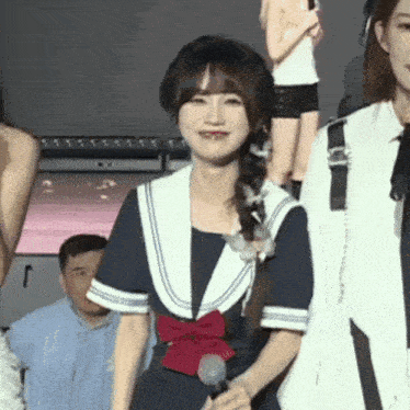 a girl in a sailor outfit is holding a microphone in her hand .