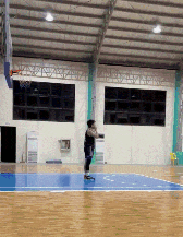 a man is playing basketball in a gym with a basketball hoop
