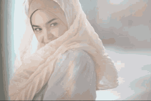 a woman wearing a white scarf around her head smiles at the camera