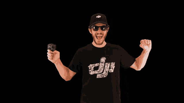 a man wearing a black dji shirt holds a camera
