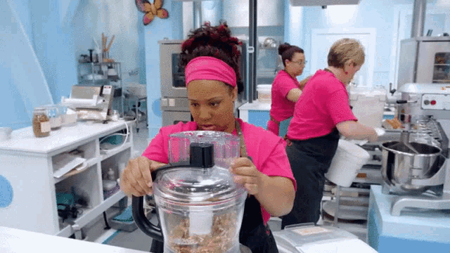 a woman in a pink apron is using a blender in a kitchen
