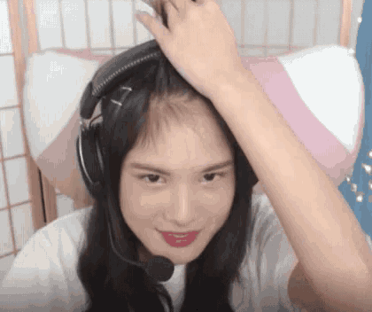 a young woman wearing headphones and a microphone looks at the camera