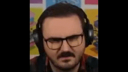 a man with a beard and glasses is wearing headphones and making a funny face .