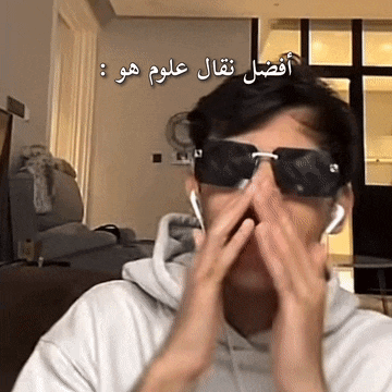 a man wearing sunglasses and ear buds is covering his face with his hands .