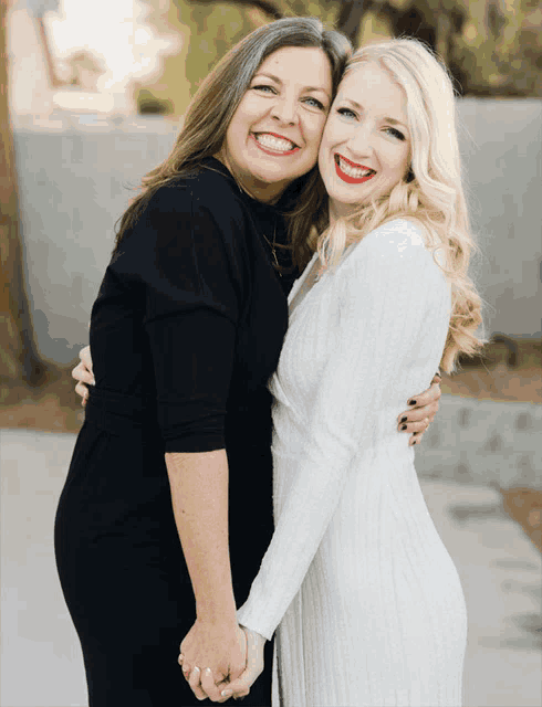 two women are posing for a picture and one of them is wearing a white dress