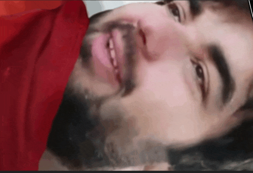 a close up of a man with a beard and a red shirt
