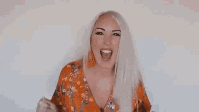 a woman in a floral dress is raising her arms in the air .
