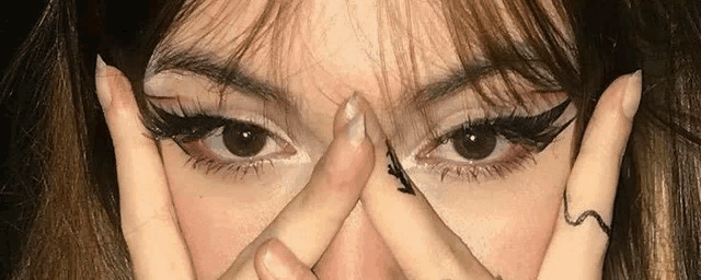 a close up of a woman 's face with her hands on her face .