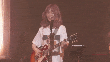 a girl is singing into a microphone while holding a guitar