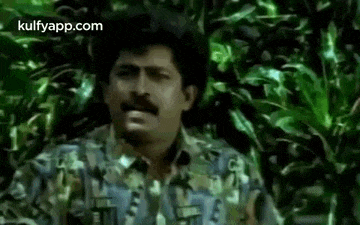 a man with a mustache is standing in a jungle .