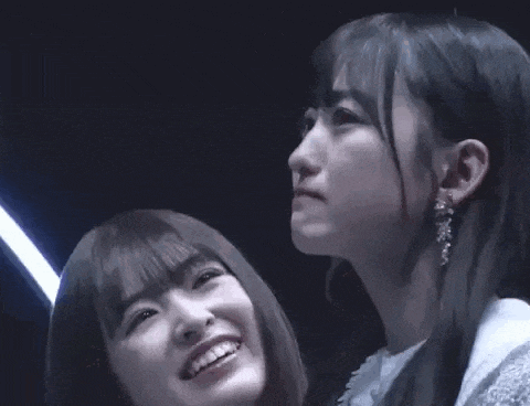 two young women are standing next to each other in a dark room .