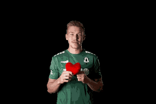 a man wearing a green telmo shirt holds two red hearts