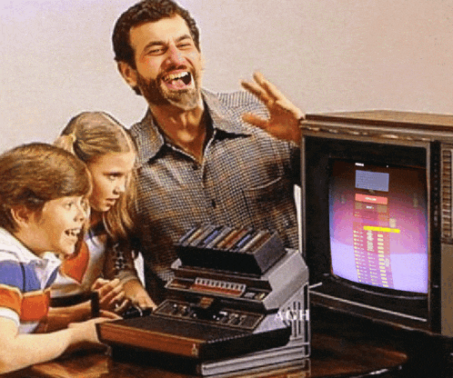a man and two children are playing a video game on an atari system