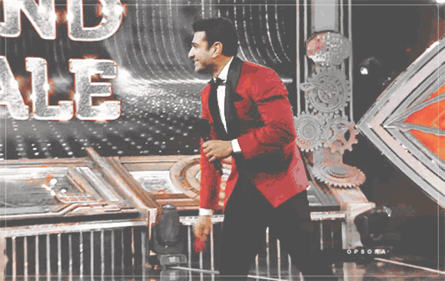 a man in a red suit is standing in front of a sign that says ' grand finale '