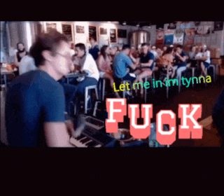 a man playing a keyboard in front of a crowd with the words " fuck " on the screen