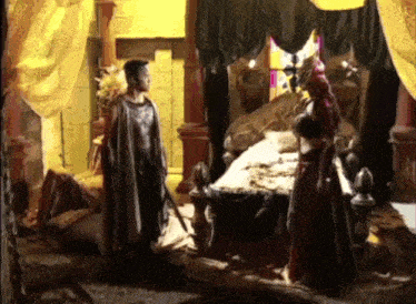 a man and a woman are standing in a room next to a bed .