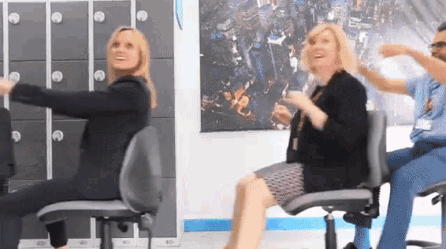 a group of women are sitting in office chairs and laughing