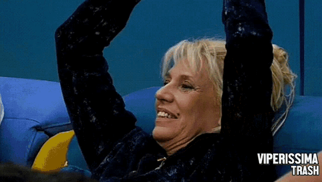 a woman is sitting on a blue couch with her arms in the air and the words viperissima trash on the bottom right