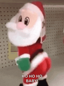 a stuffed santa claus is standing on a shelf in a store and holding a green cup .