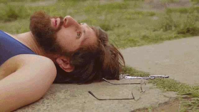 a man with a beard is laying on the ground with his head on the ground .