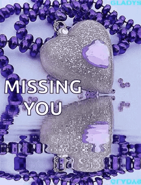 a purple necklace with a heart shaped pendant and the words `` missing you '' written on it .