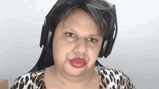 a woman wearing headphones and red lipstick looks at the camera .