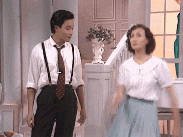 a man wearing suspenders and a tie stands next to a woman
