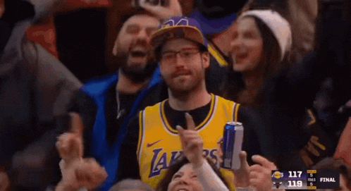 a man in a lakers jersey holds a red bull can