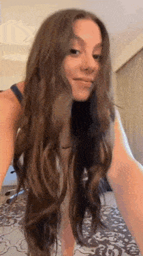 a woman with long brown hair is taking a selfie in a hotel room .
