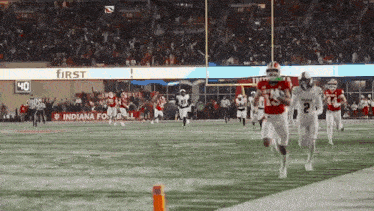 a football game is being played in front of a sign that says first bank