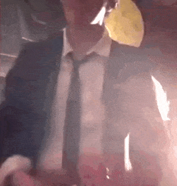 a man in a suit and tie is smoking a cigarette in a dark room