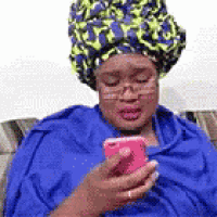 a woman wearing a turban is sitting on a couch holding a cell phone .