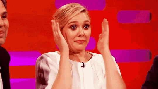 a woman is making a funny face while clapping her hands in front of a red background .