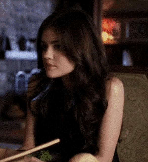 a woman is sitting on a couch holding chopsticks