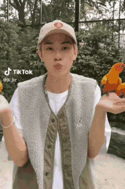 a man wearing a hat and vest is holding a parrot in his hands .