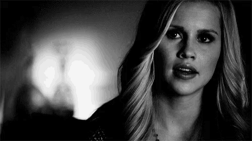 a black and white photo of a woman looking at the camera with a surprised look on her face .