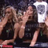 a group of women are sitting in a stadium watching a basketball game and making funny faces .