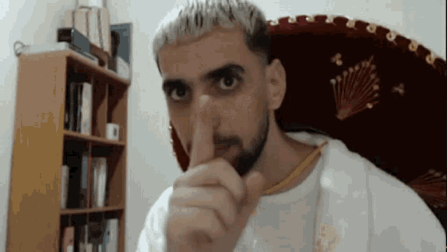 a man with a beard is making a shhh gesture with his finger