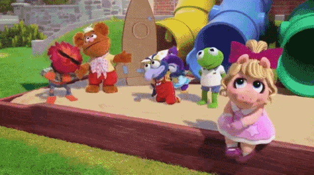 a group of sesame street characters are standing on a sandbox