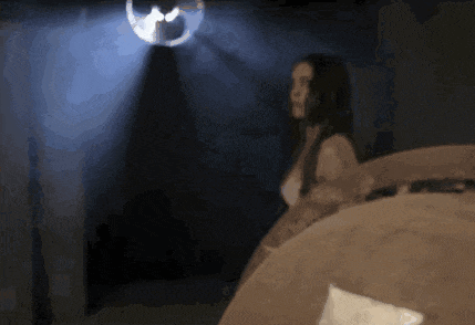 a woman standing in a dark room with a light shining on her head