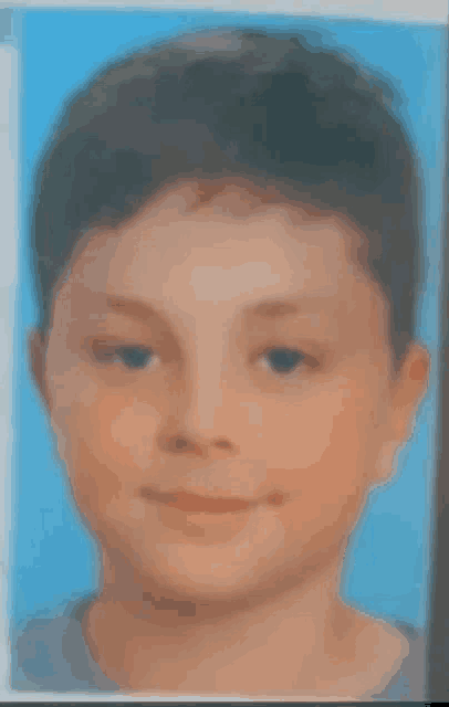 a young boy is smiling for the camera in a blue background .